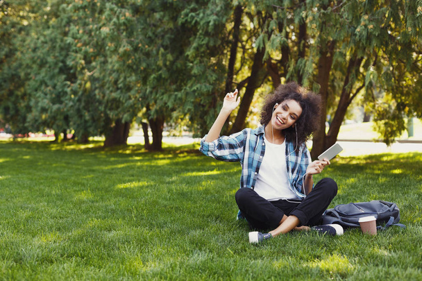 Jeune femme écoutant de la musique sur l'herbe à l'extérieur
 - Photo, image