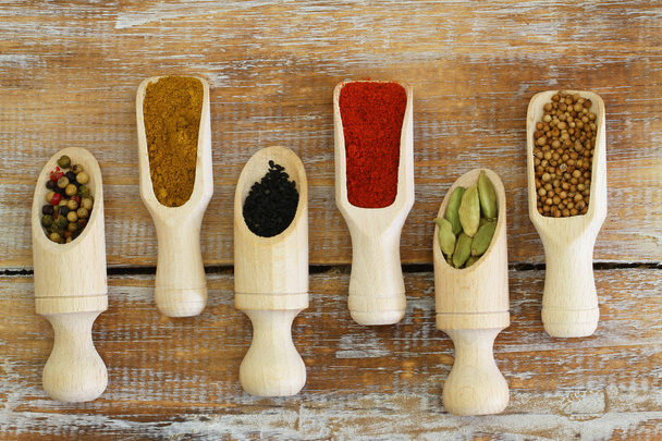 Indian spices on wooden scoops on wooden surface - Photo, Image