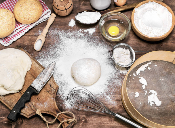 scattered wheat flour on the table, next to raw yeast dough  - Photo, Image