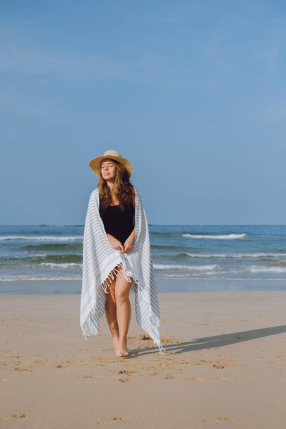 Girl in a hat walking along the beach - Φωτογραφία, εικόνα