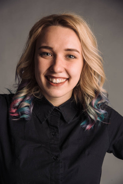 portrait of smiling young woman with colored hair in black shirt isolated on gray studio background posing to the camera - Фото, изображение