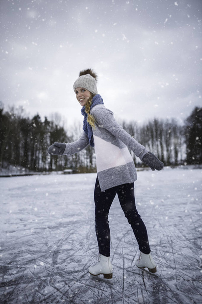 Young woman ice skating outdoors on a pond on a freezing winter  - Foto, afbeelding