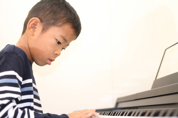 Japanilainen poika soittaa pianoa (toinen luokka ala-asteella
) - Valokuva, kuva