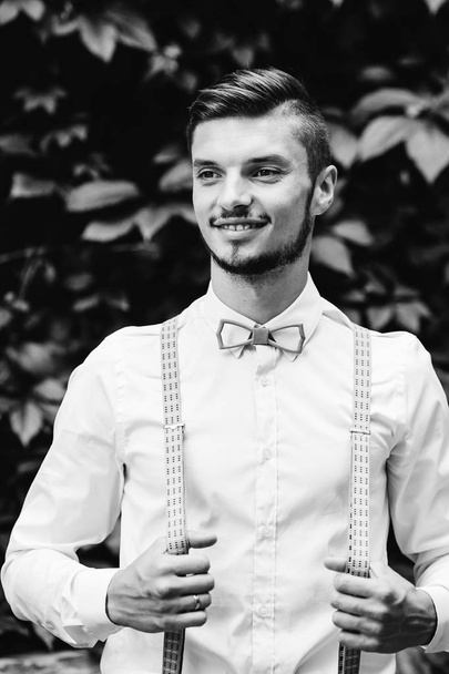 guy with wooden bow tie and suspenders smiles on a black and white photo - Photo, Image