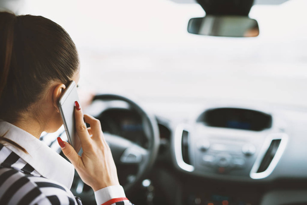 όμορφη νεαρή επιχειρηματίας οδήγηση του αυτοκινήτου και μιλώντας μέσω του κινητού τηλεφώνου - Φωτογραφία, εικόνα