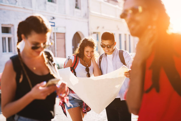 group of young happy friends travelling together and looking at city map - Fotó, kép