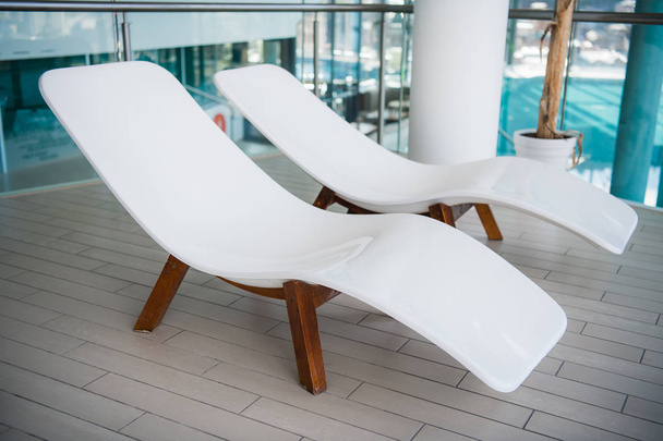 Modern deck chairs at luxury hotel. Private swimming pool for relaxation, with beautiful interior. - Photo, Image