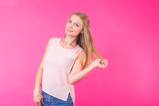 Pretty young woman smiling against a pink background. - Photo, Image