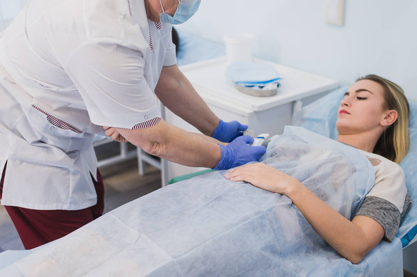 Enfermera fijando tubo intravenoso a los pacientes mano en cama de hospital
 - Foto, Imagen