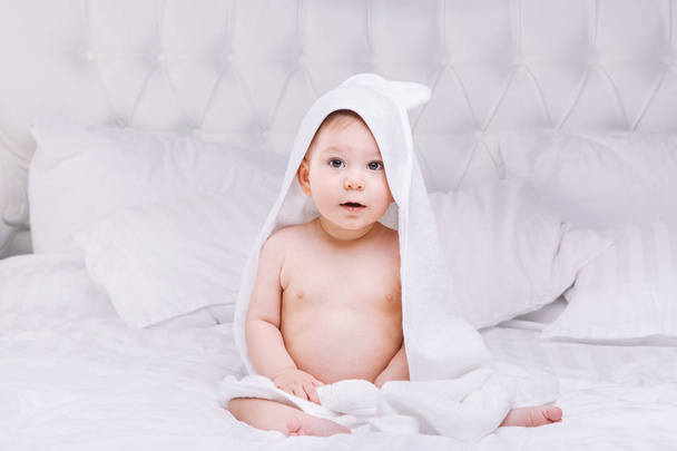 Adorably baby lie on white towel in bed. Happy childhood and healthcare concept. - Photo, image