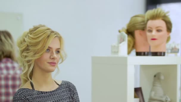 Ładna Blondynka patrzy w lustro w salonie piękności - Materiał filmowy, wideo
