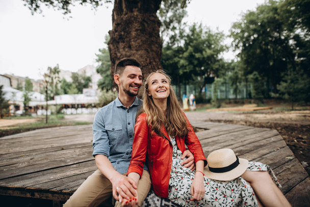 Veselý mladík a dívka tráví čas spolu sedí u stromu v parku. Příběh lásky - Fotografie, Obrázek