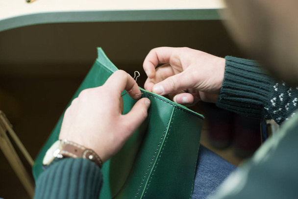 hombre haciendo en proceso hecho a mano bolsa de cuero verde
 - Foto, imagen