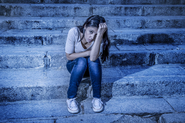 Редактированный экспрессионистский портрет молодой грустной и подавленной женщины или девушки-подростка, сидящей в одиночестве на улице и выглядящей отчаявшейся и страдающей.
  - Фото, изображение
