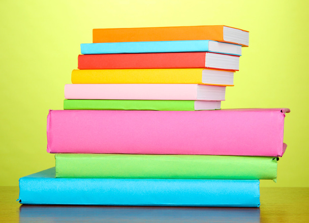 Stack of multicolor books on green background - Photo, image