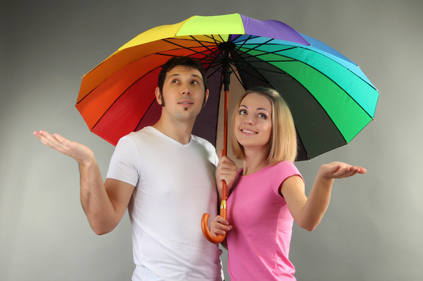 Loving couple with umbrella on grey background - Foto, afbeelding