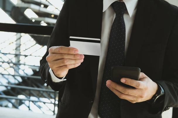 homem segurando um cartão de crédito e usando telefone inteligente para compras on-line
 - Foto, Imagem