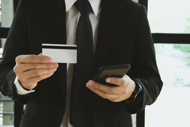 uomo in possesso di una carta di credito e utilizzando lo smart phone per negozio online
 - Foto, immagini
