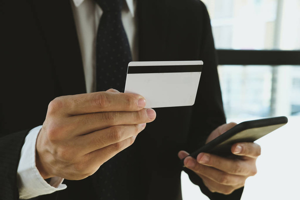 hombre sosteniendo una tarjeta de crédito y el uso de teléfono inteligente para compras en línea
 - Foto, imagen