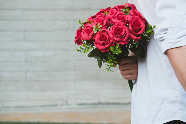 man holding bouquet of red roses behind his back. boyfriend surp - Photo, Image