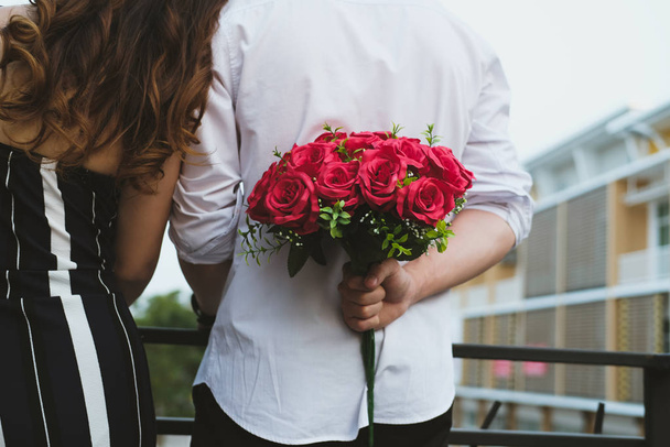 man holding bouquet of red roses behind his back. boyfriend surp - 写真・画像
