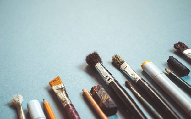 on a blue table are many art brushes of different sizes - 写真・画像