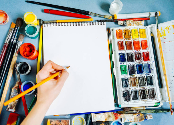 woman artist paints on paper with a brush and bright watercolors - Photo, Image