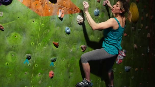 Een vrouwelijke rotsblok traint om obstakels te overwinnen op de muur voor klimmers. Professionele hulpverlener. Klimmuur. Slow motion - Video