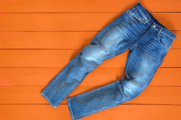 Mężczyźni niebieski jeans denim spodnie na pomarańczowym tle. Satur kontrast - Zdjęcie, obraz