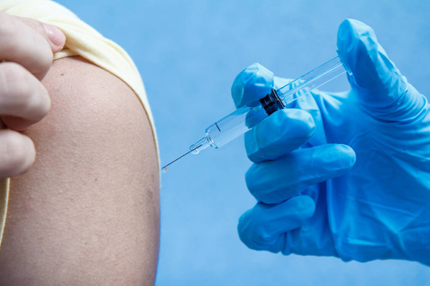Mano del medico che tiene la siringa per la vaccinazione nella parte superiore del braccio di p
 - Foto, immagini