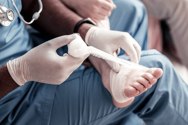Skaalattu ilme lääkäri bandaging jalka
 - Valokuva, kuva