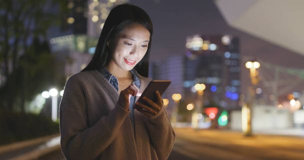 Молода жінка дивиться на мобільний телефон у місті
  - Фото, зображення