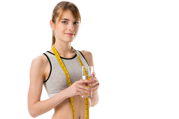 young slim woman wih measuring tape holding glass of water isolated on white - Foto, Imagen