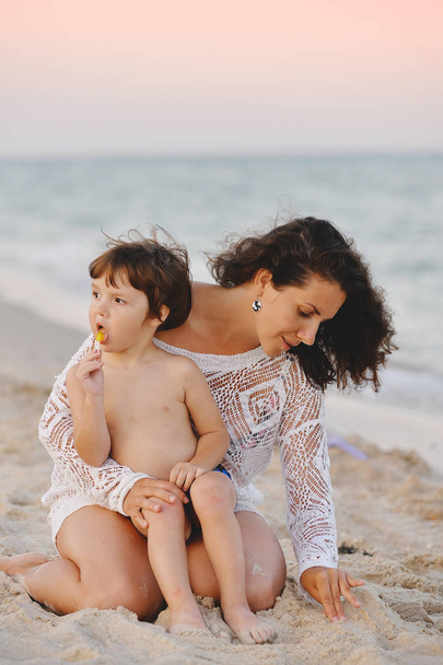 mom with baby sitting on the beach and playing sand in summer - Фото, зображення