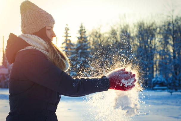 Ένα νεαρό κορίτσι με τα κόκκινα γάντια παλαμάκια με χιόνι. Χειμερινής περιόδου - Φωτογραφία, εικόνα