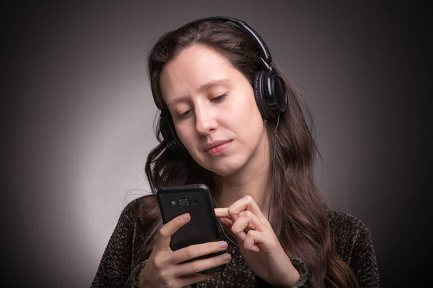 Beautiful girl listening to music with headphones on smartphone - Zdjęcie, obraz