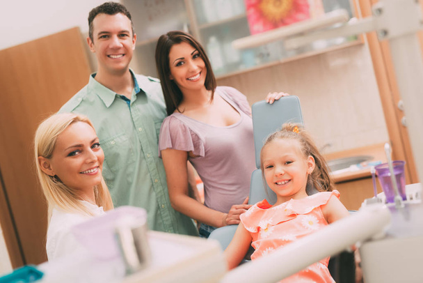 Happy young family at visit in the dentist office. They are  looking at camera. - Photo, Image