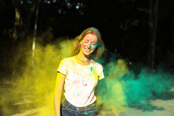 Jovem alegre brincando com tinta seca amarela e verde Hol
 - Foto, Imagem