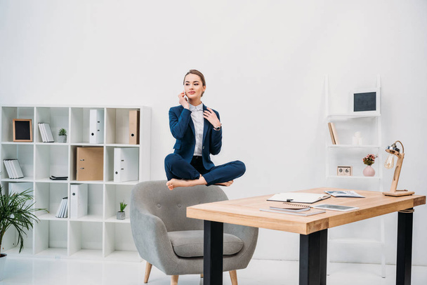 beautiful young businesswoman talking by smartphone while levitating at workplace  - Photo, Image