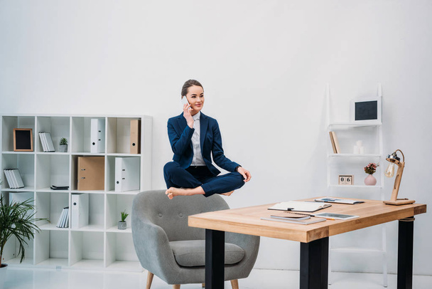 businesswoman talking by smartphone while levitating at workplace  - Valokuva, kuva