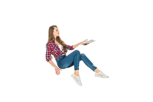 όμορφο κορίτσι χρησιμοποιώντας ψηφιακό tablet ενώ αιωρούμενο απομονωθεί σε λευκό - Φωτογραφία, εικόνα