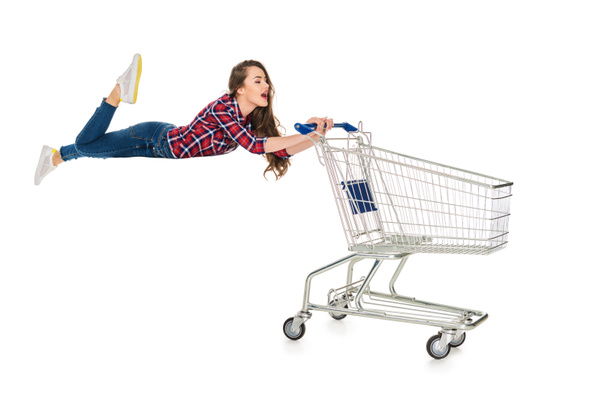 young woman levitating with empty shopping trolley isolated on white - 写真・画像