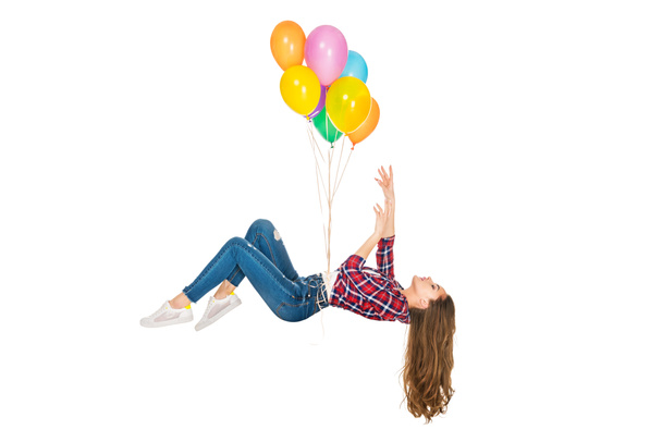 junge Frau schwebt mit bunten Luftballons auf weißem Grund - Foto, Bild