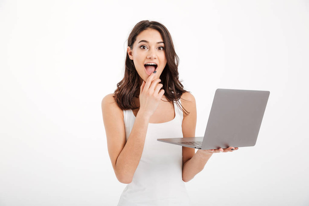 Portrait of an excited girl dressed in tank-top using laptop - Foto, afbeelding