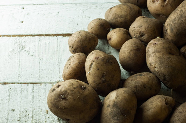 A lot of dirty potatoes on a rustic background. - 写真・画像