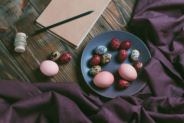 Barevná velikonoční vajíčka s lněným hadříkem na rustikální hnědý dřevěný stůl. Dovolená pozadí. - Fotografie, Obrázek
