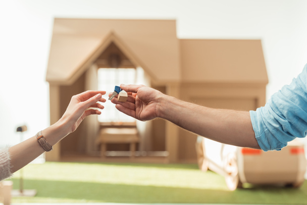 cropped shot of real estate agent passing key to client in front of cardboard house - Photo, Image