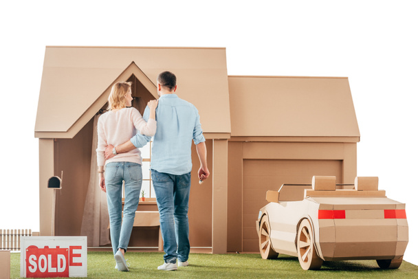 rear view of couple walking to their new cardboard house isolated on white - Foto, Imagem
