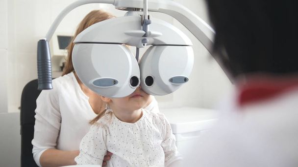 Okulistyka dzieci - okulista sprawdza oko z małą dziewczynką - Zdjęcie, obraz