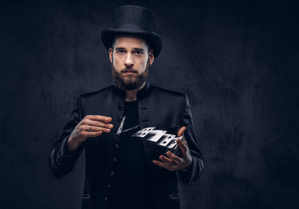 Magician showing trick with playing cards on a dark background. - Photo, Image
